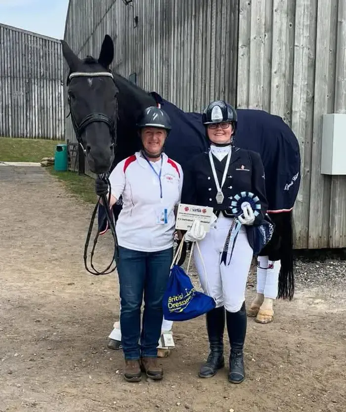 two riders standing with a horse